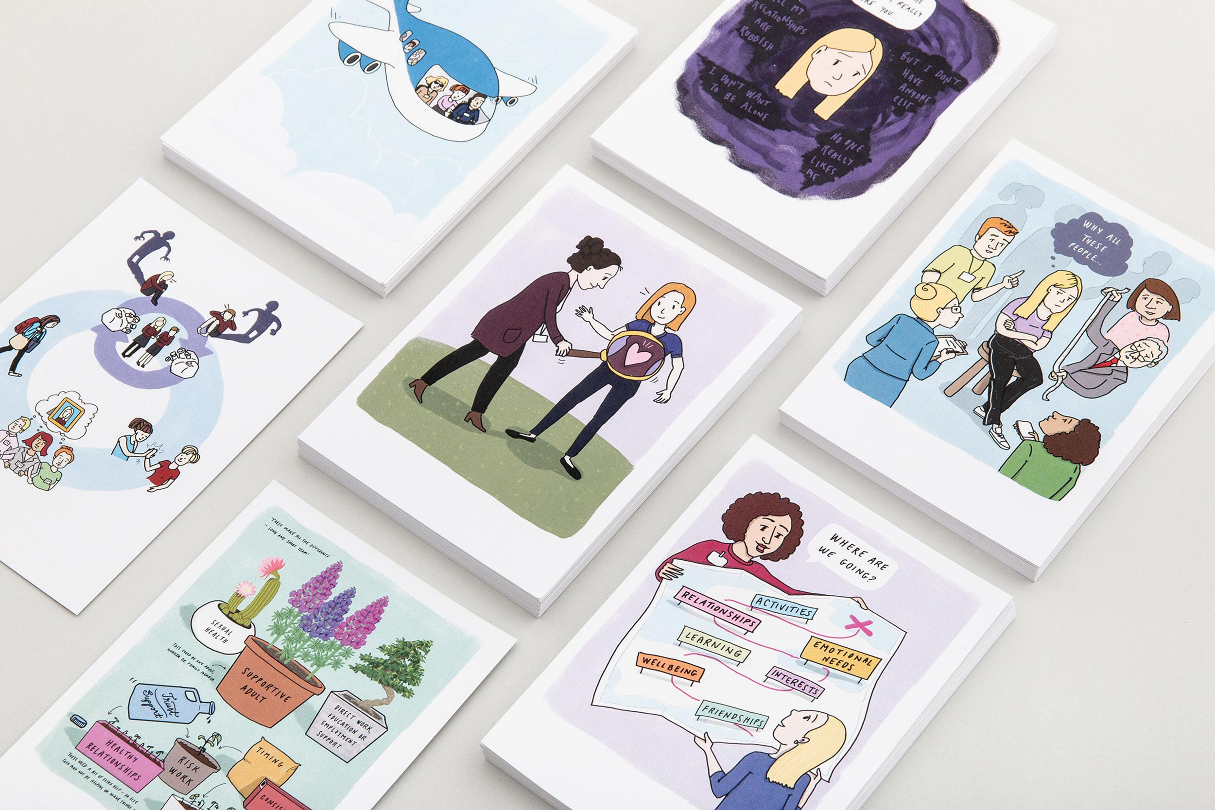 Stacks of postcards on a table with different illustrations on them about young people and safeguarding