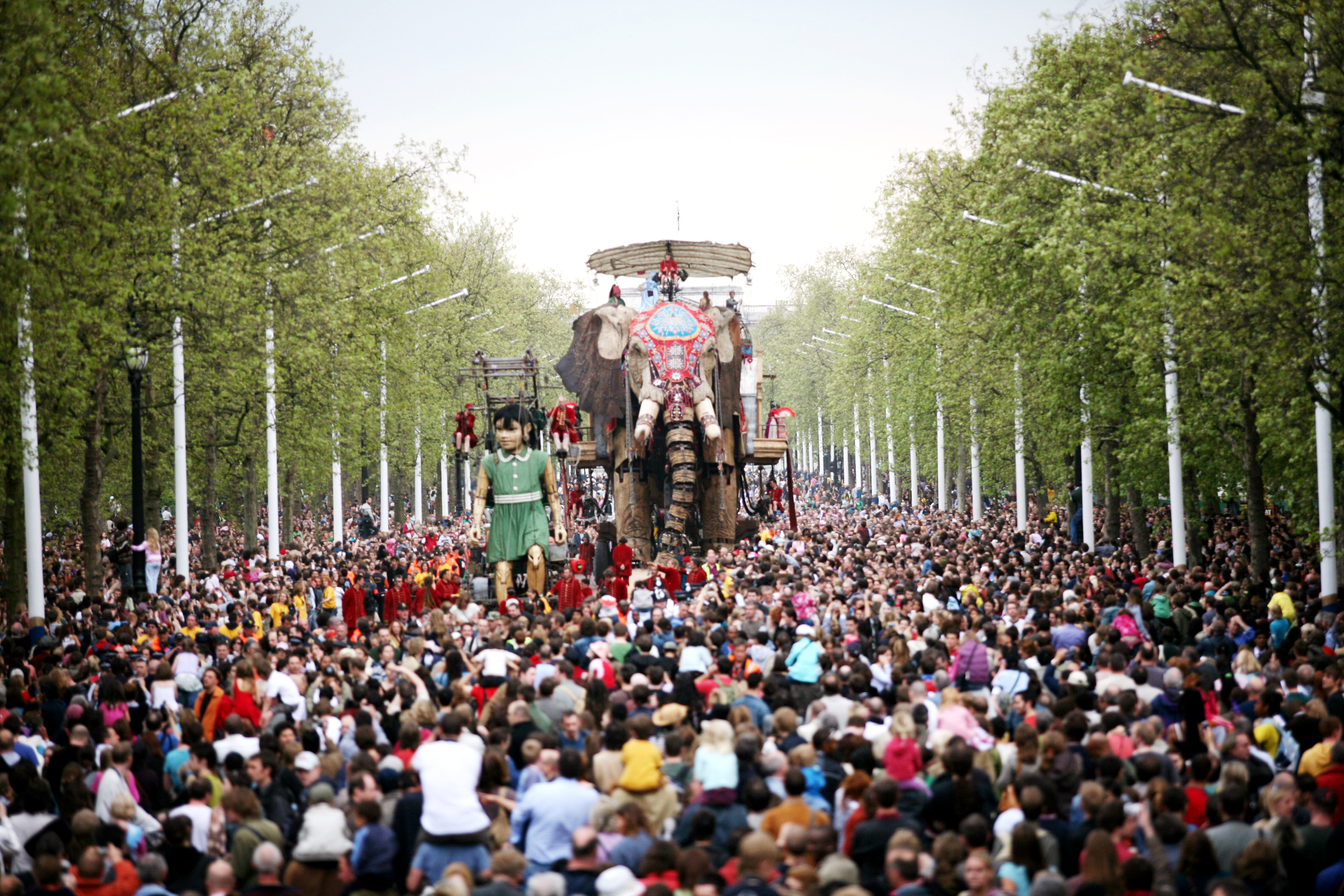 A huge mechanical puppet of an elephant and a girl moving through busy London streets
