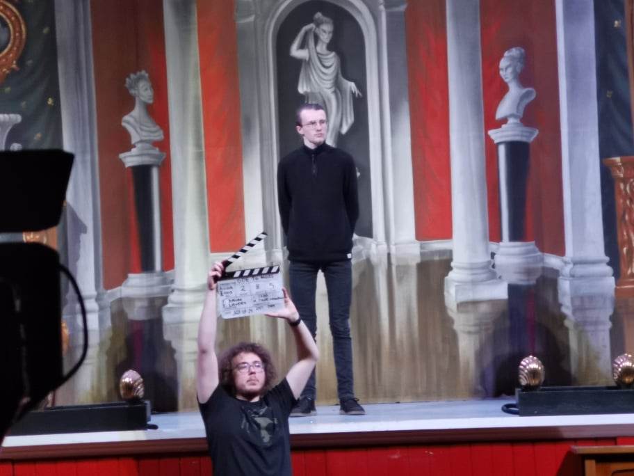 Behind the scenes of 'Ode to Moss' (2023). Matthew is holding a clapperboard in front of an actor.