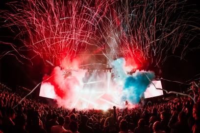 Stage at a festival with red and blue smoke and lights