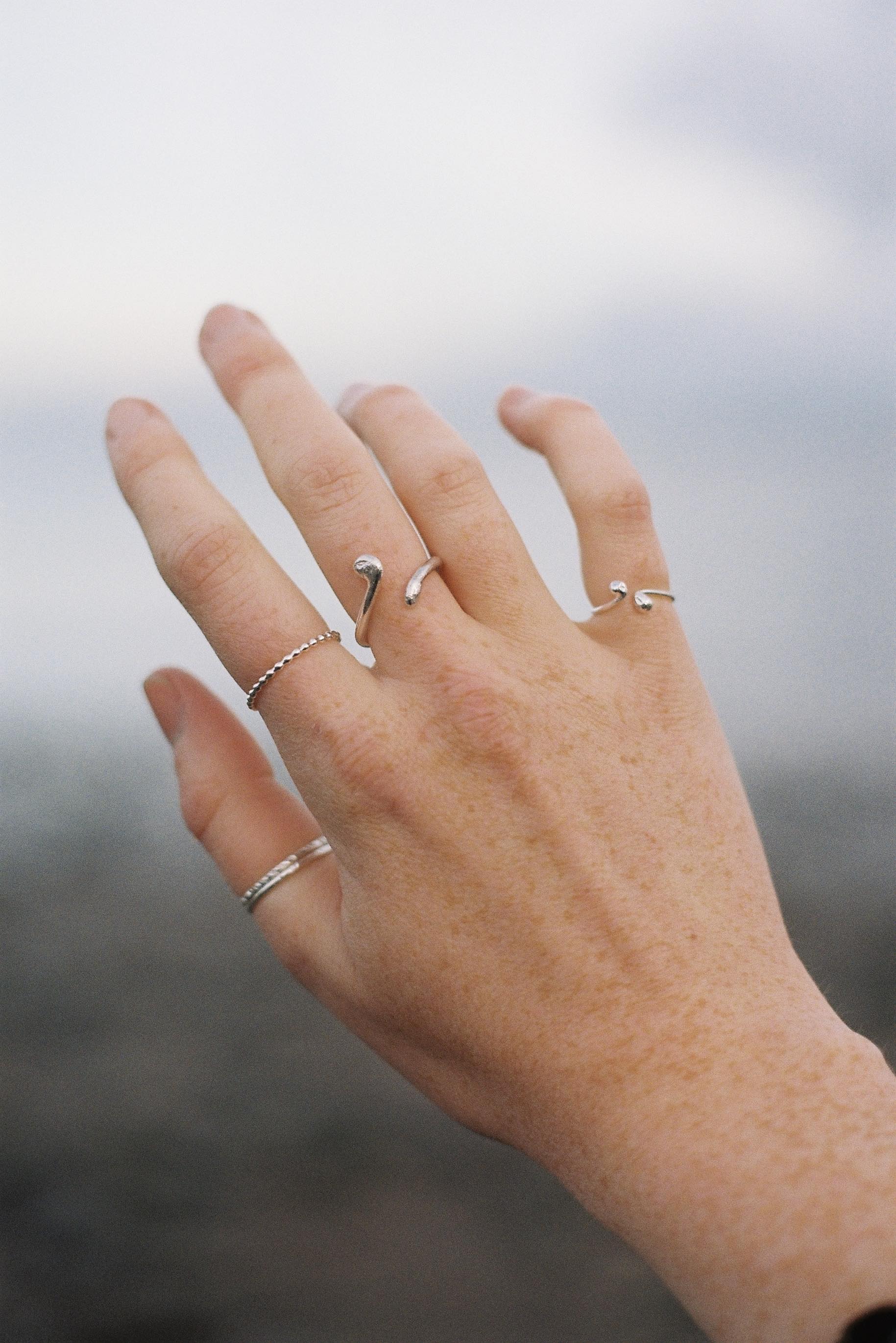 a pale hand with lots of adjustable silver rings on