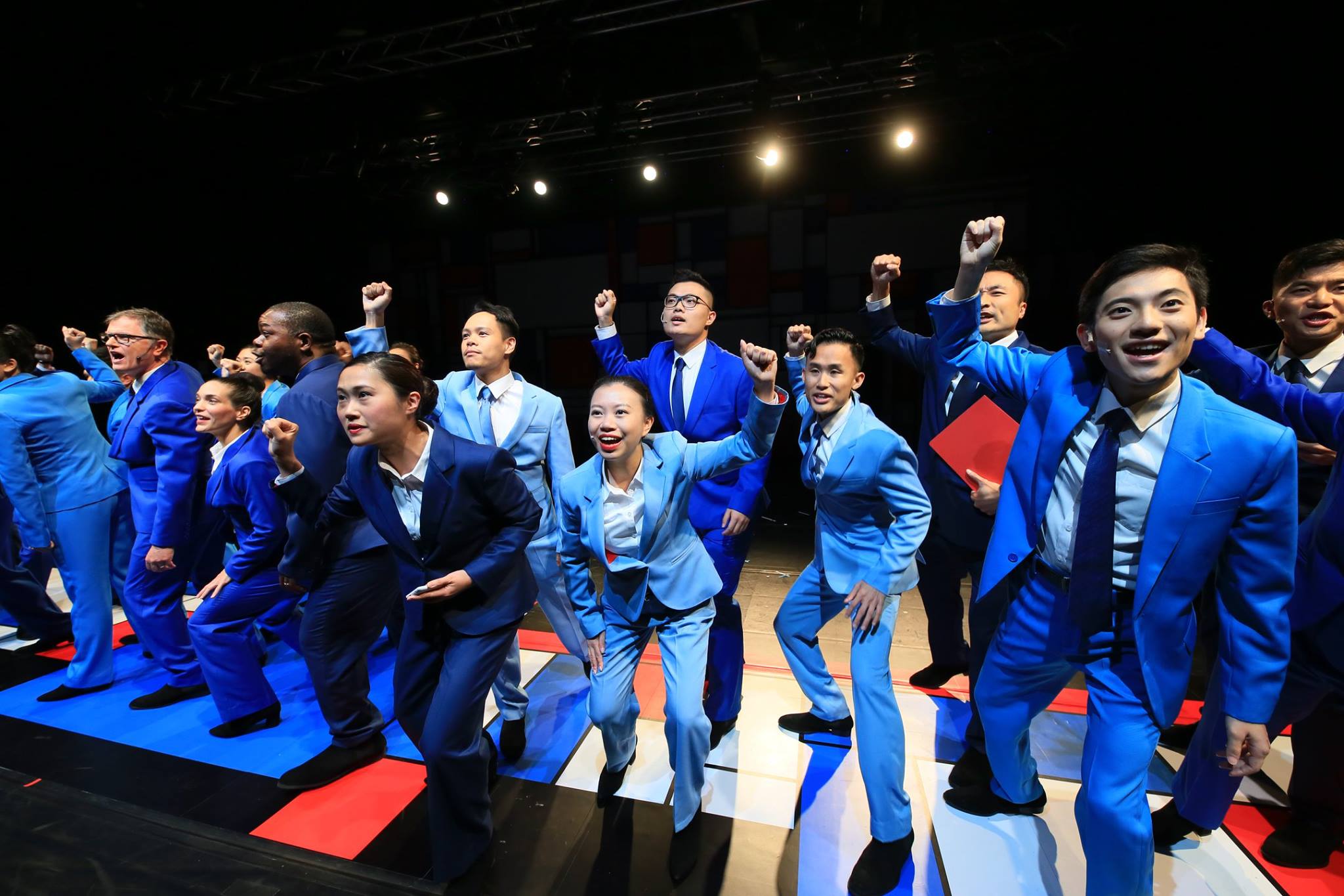 Neil with Hong Kong performers all wearing blue suits in an office musical.