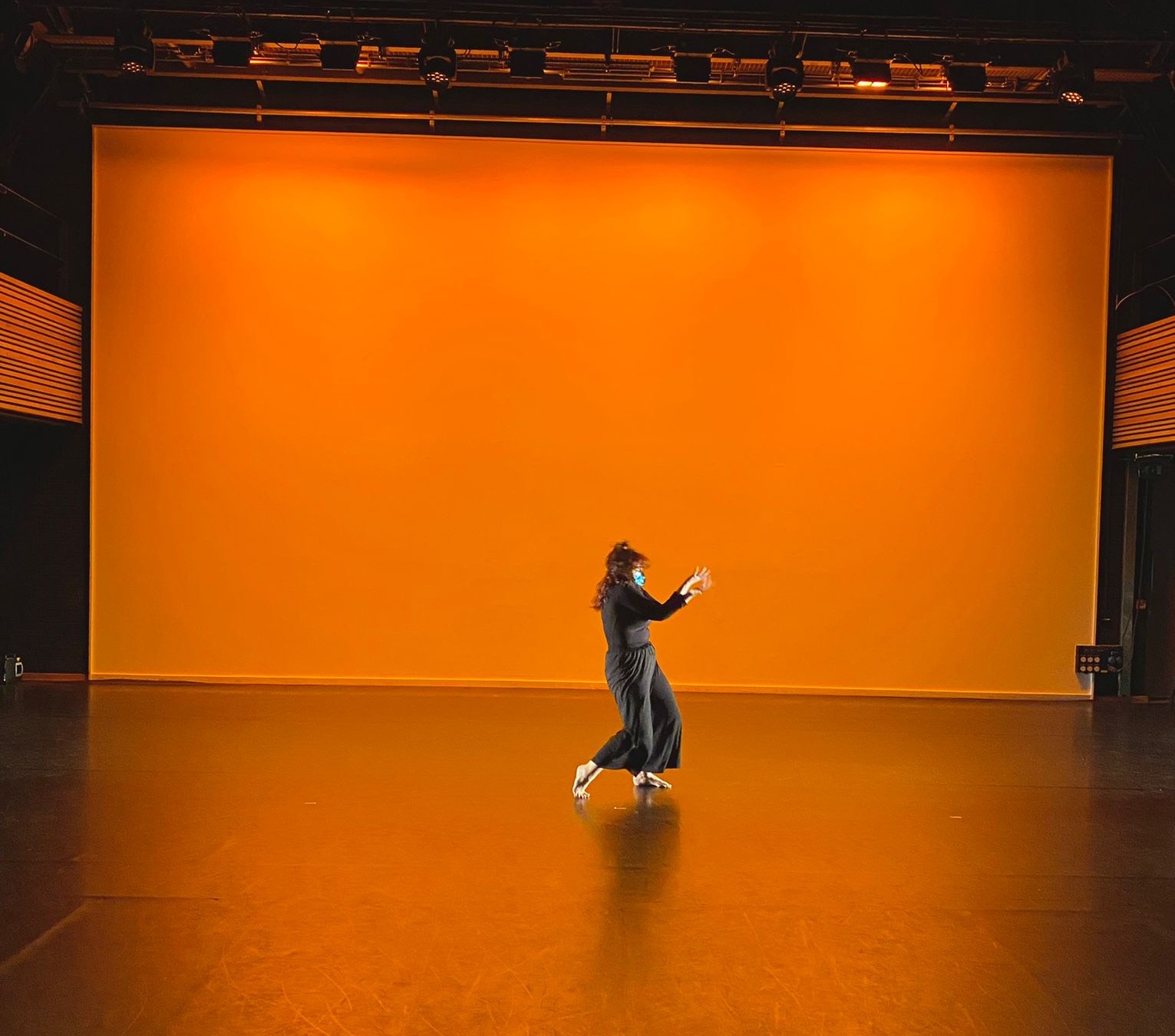 One person on an orange lit stage wearing all black