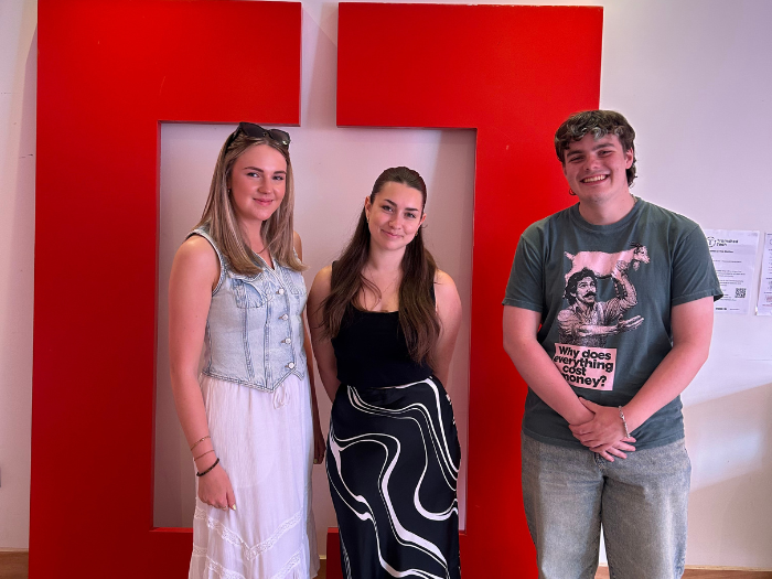Katie, Danielle and Brett stood in front of the Creative Cardiff logo