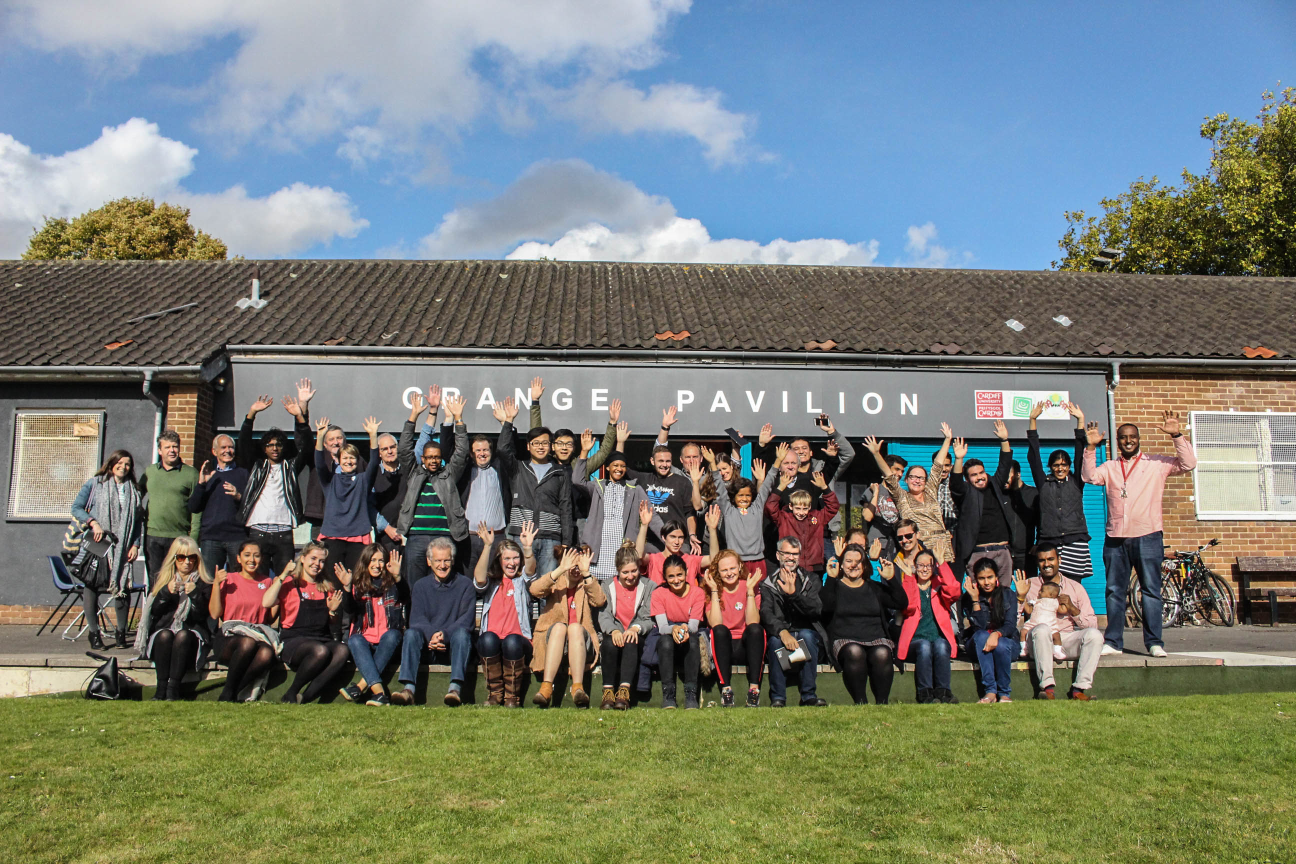 A group of Grangetown residents with hands in the air outside Grange Pavilion building