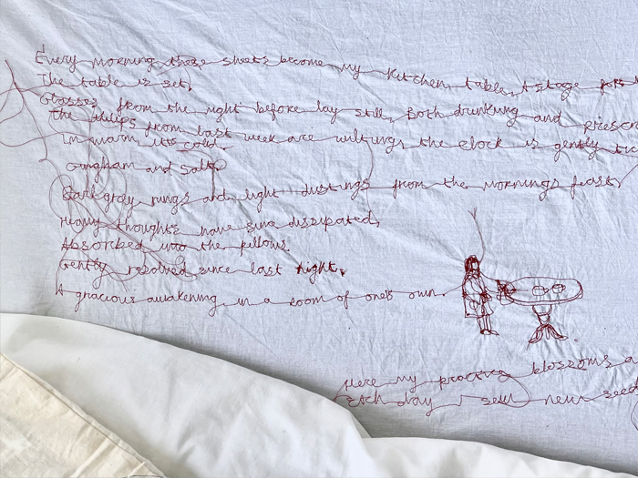 A white sheet with red, embroidered writing on it.